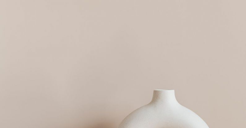 Home Studio Maintenance - White ceramic vase in creative shape of ring placed on white marble stand against beige wall as home decoration element or art object