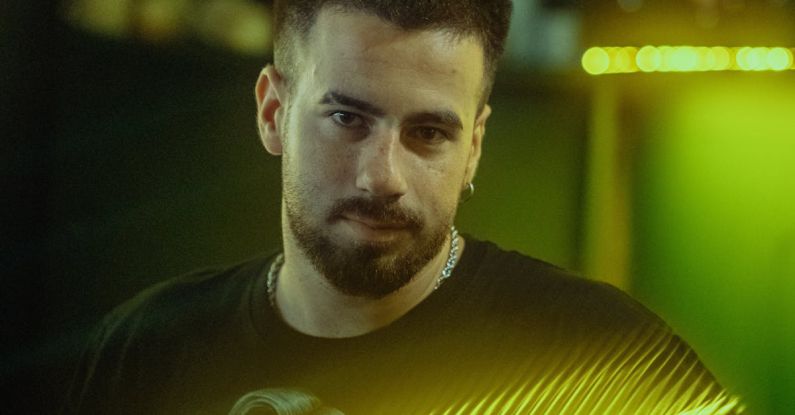 DJ Library - A man with a beard standing in front of a bar