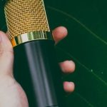 Sound Quality - Crop anonymous person showing modern recorder in hand against green leaf of plant in daylight