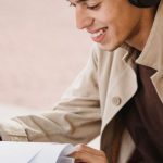 Wireless Audio - Smiling student smiling happily while preparing homework project while listening to music in wireless headphones