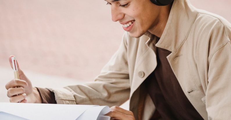 Wireless Audio - Smiling student smiling happily while preparing homework project while listening to music in wireless headphones