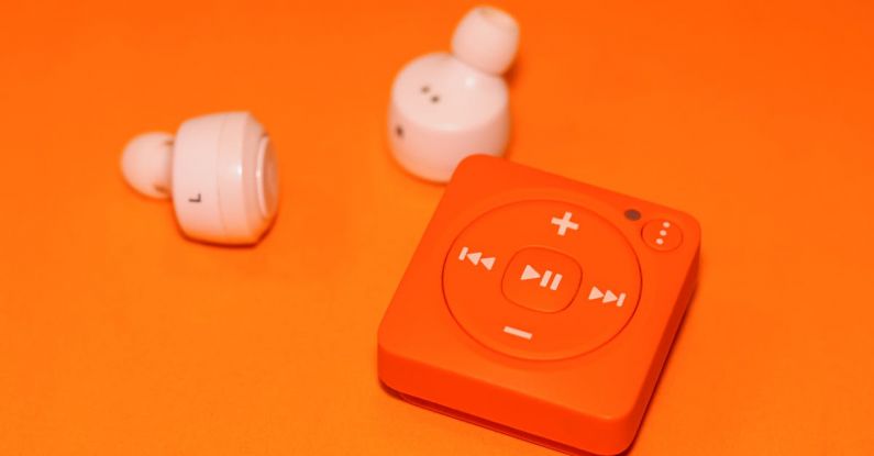 MP3 Compression - White Earphones Beside Orange Music Player