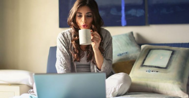 Streaming Platforms - Woman in Grey Jacket Sits on Bed Uses Grey Laptop