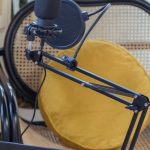 Digital Audio Formats - Modern laptop and microphone on tripod placed near wicker chair in modern studio before recording podcast
